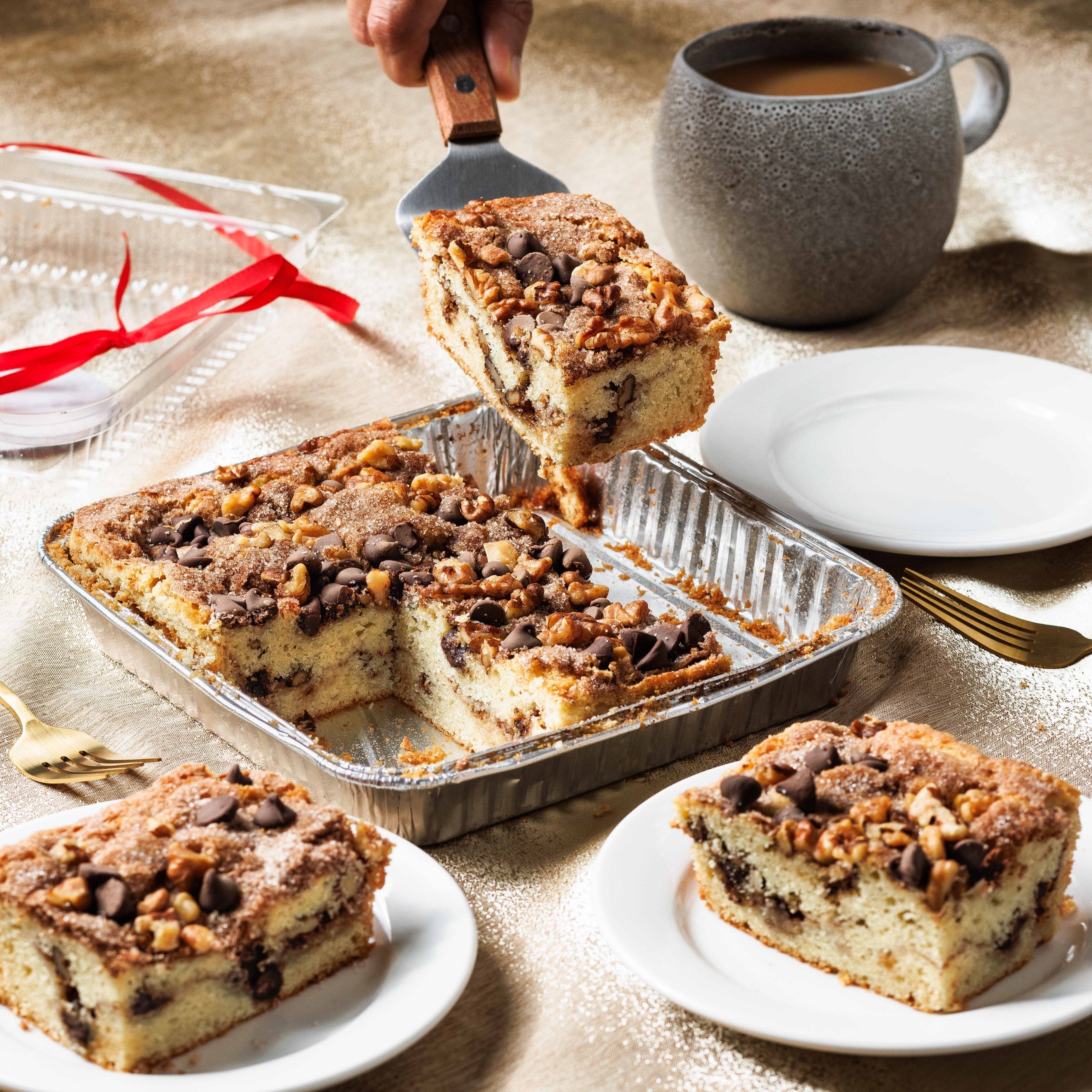 Whole Sour Cream Coffee Cake being served on white plates. So moist and delicious, sour cream coffee cake full of chocolate, walnuts, cinnamon and sugar streusel, with coffee.  This super moist coffee cake is the best coffee cake. Best coffee cake san diego, best coffee cake recipe, best coffee cake ever, sour cream coffee cake, sour cream coffee cake moist and delicious, best cookies san diego, best cookies near me, best cookies la jolla, best cookies carlsbad, 