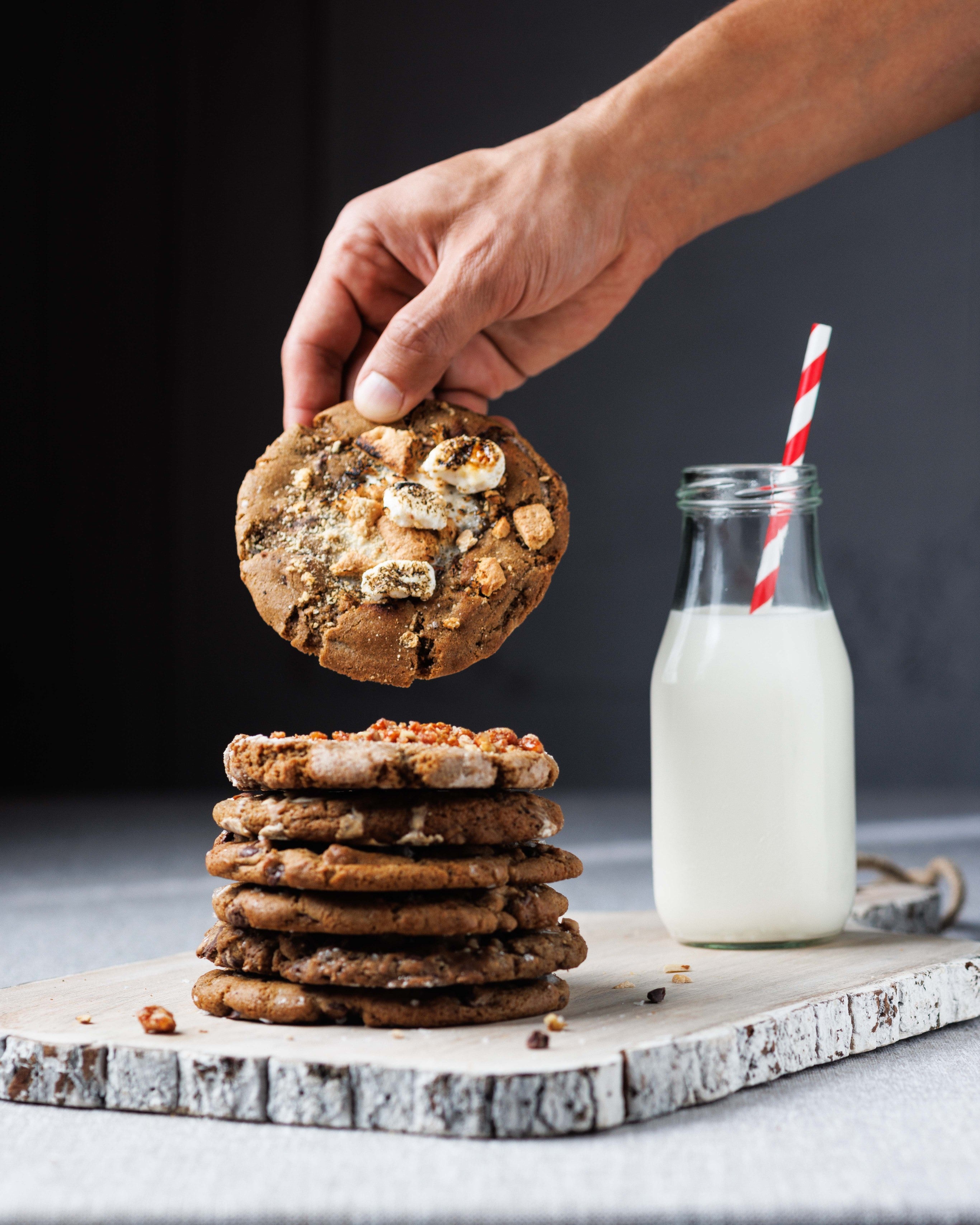 Gooey Smores cookie dipping into milk. best gooey smores s'mores cookie in san diego, best cookies in la jolla, best baked goods san diego, best bakery san diego, chewy chocolate chip cookies for shipping, cookie delivery, gourmet cookies, chef crafted flavors, at the la jolla open aire market