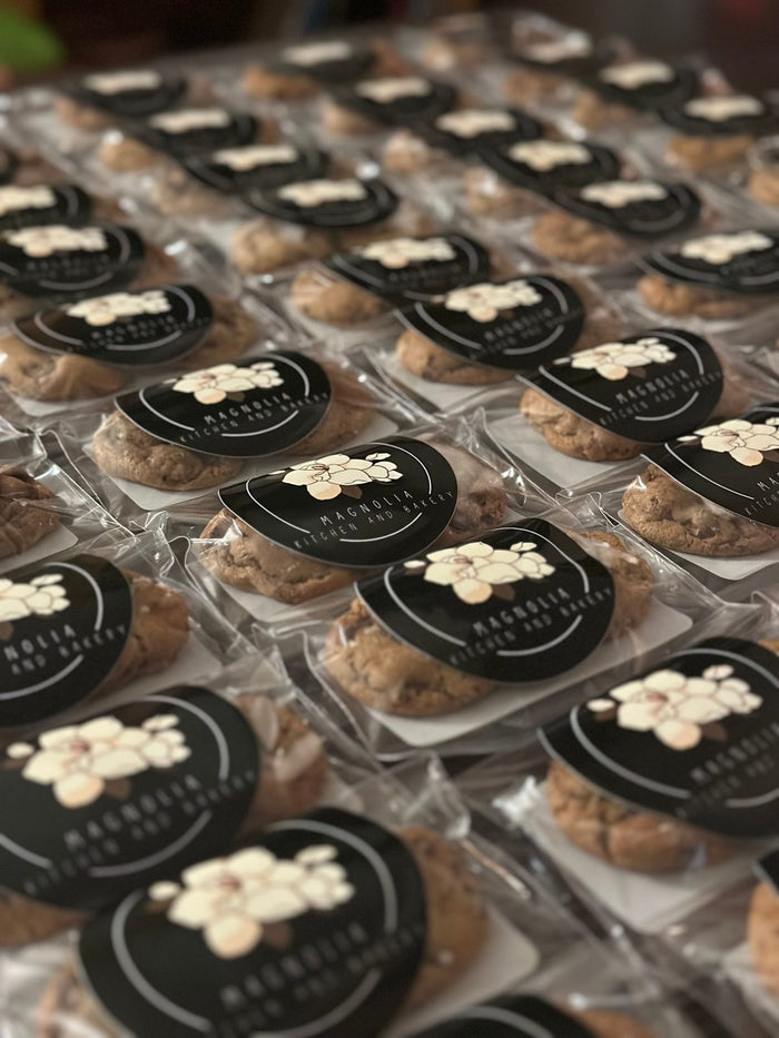 Rows of individually wrapped Magnolia Kitchen and Bakery cookies with black magnolia logo labels